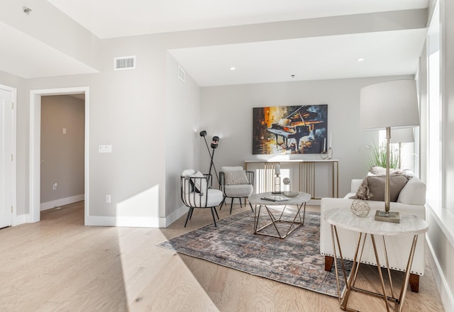 living area with baseboards, visible vents, and light wood-style floors