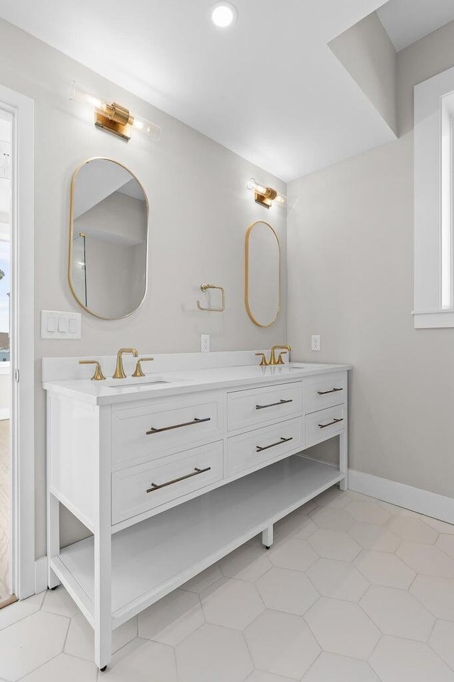 full bathroom featuring double vanity, baseboards, and a sink