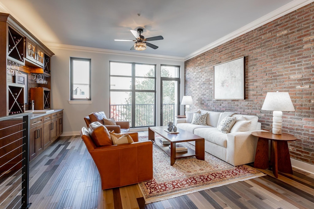 living area featuring brick wall, ornamental molding, dark wood-style flooring, and a wealth of natural light