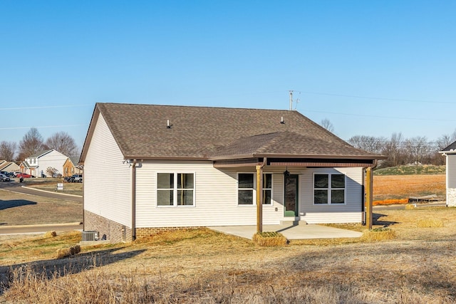 back of house featuring roof with shingles, central air condition unit, a patio, and a lawn