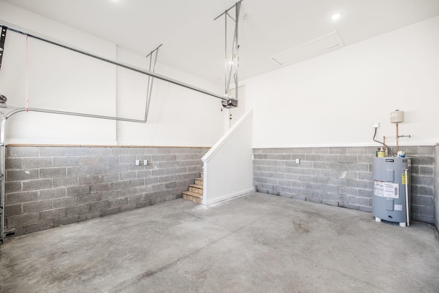 garage with concrete block wall, a garage door opener, and water heater