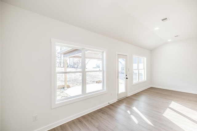 interior space featuring baseboards, a wealth of natural light, lofted ceiling, and light wood-style floors