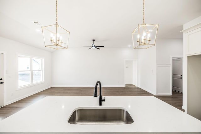 kitchen with a sink, light countertops, an inviting chandelier, and pendant lighting