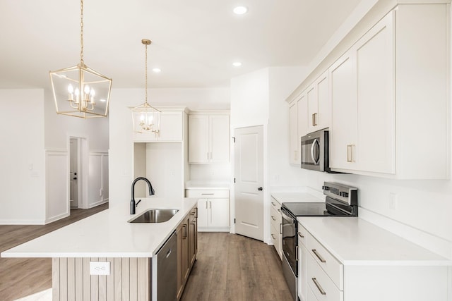 kitchen with a kitchen island with sink, stainless steel appliances, a sink, and light countertops