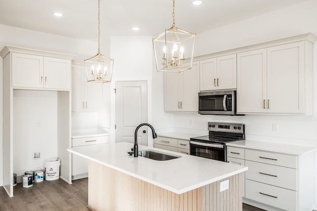 kitchen with a sink, a kitchen island with sink, stainless steel appliances, and light countertops