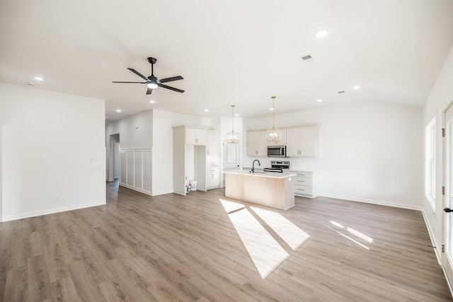 kitchen with open floor plan, light countertops, a center island with sink, appliances with stainless steel finishes, and white cabinetry