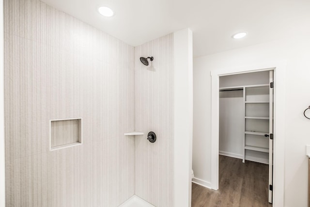 bathroom featuring a tile shower, recessed lighting, wood finished floors, and a spacious closet