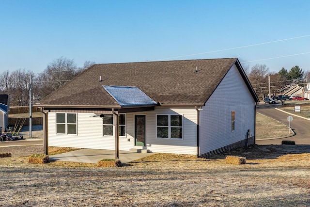 view of front facade featuring a patio area and roof with shingles