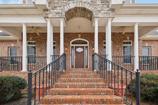 view of exterior entry featuring stone siding, covered porch, brick siding, and ceiling fan