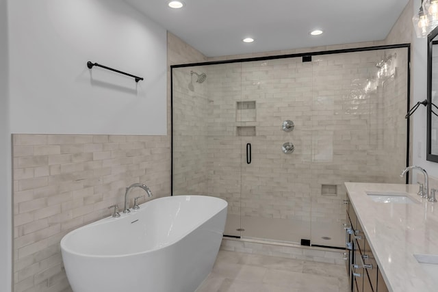 full bathroom with tile walls, recessed lighting, a freestanding bath, a stall shower, and vanity