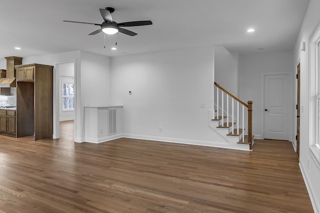 unfurnished living room featuring dark wood-style floors, stairway, and recessed lighting