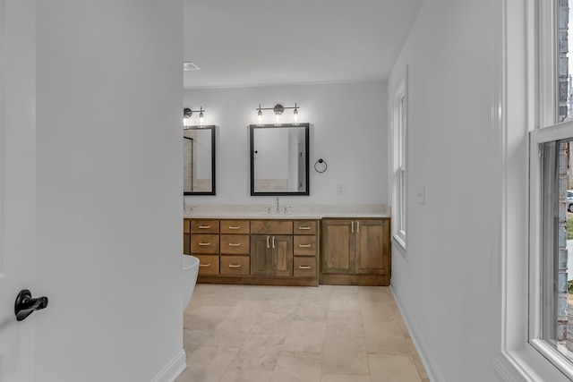 full bath featuring baseboards, a freestanding bath, and vanity