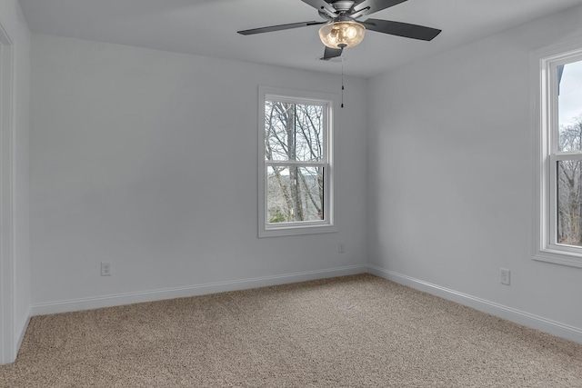 carpeted empty room with ceiling fan and baseboards