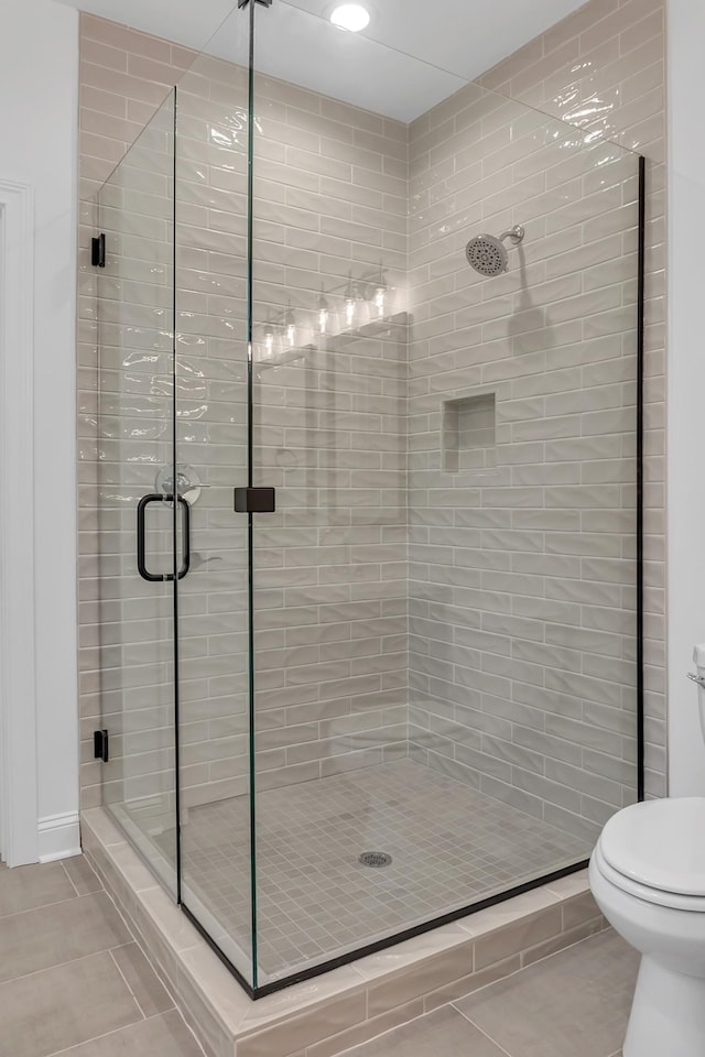 bathroom with toilet, a shower stall, and tile patterned flooring