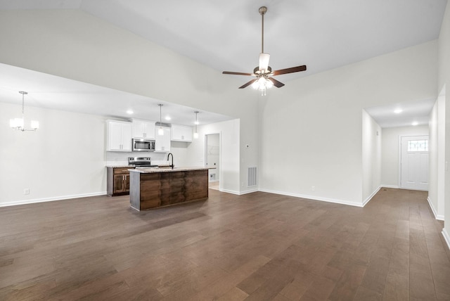 kitchen with stainless steel appliances, white cabinets, open floor plan, light countertops, and an island with sink