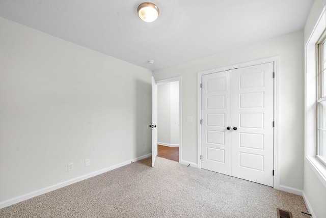 unfurnished bedroom with a closet, carpet, visible vents, and baseboards