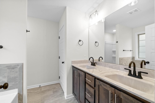 full bathroom with double vanity, a sink, visible vents, and baseboards