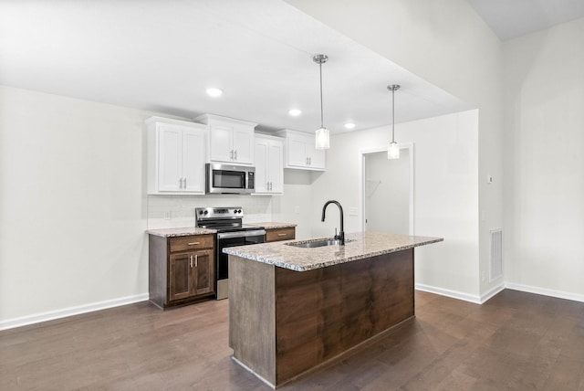 kitchen with a kitchen island with sink, stainless steel appliances, a sink, white cabinets, and light stone countertops