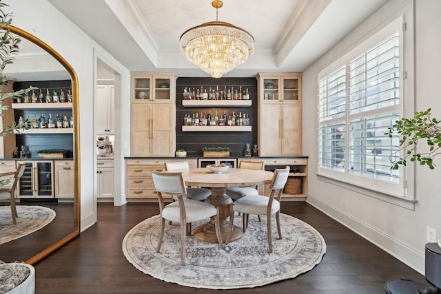 dining space featuring beverage cooler, a bar, a tray ceiling, and dark wood finished floors