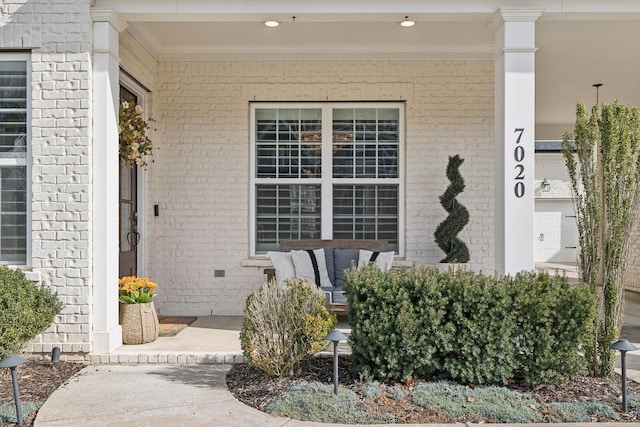 doorway to property with a porch and brick siding