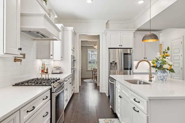 kitchen with custom range hood, appliances with stainless steel finishes, light countertops, white cabinetry, and a sink