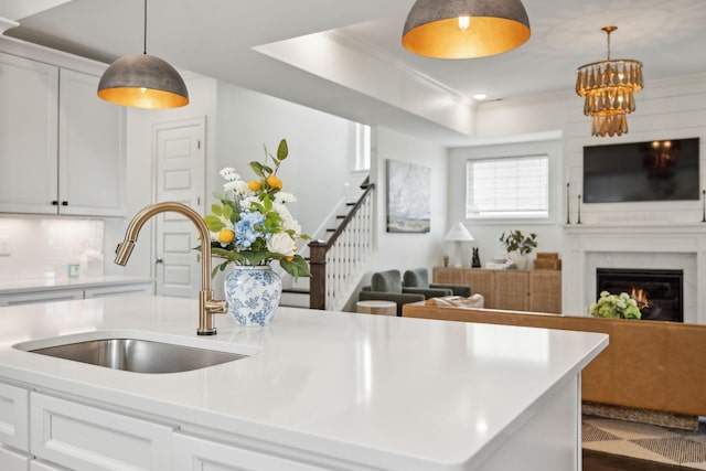 kitchen with light countertops, open floor plan, white cabinetry, a sink, and an island with sink