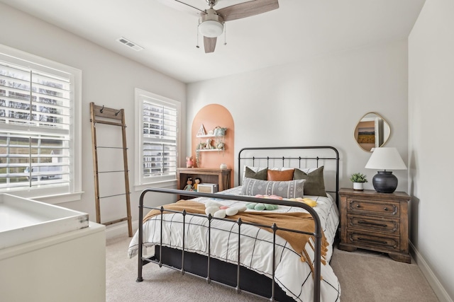 bedroom with light carpet, ceiling fan, visible vents, and baseboards