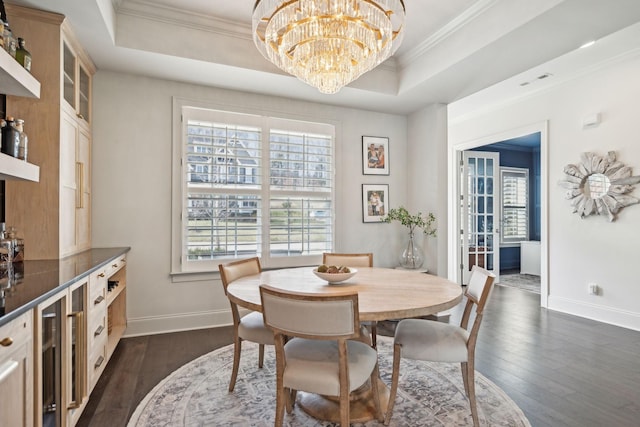 dining room featuring dark wood-style floors, a raised ceiling, a wealth of natural light, and crown molding