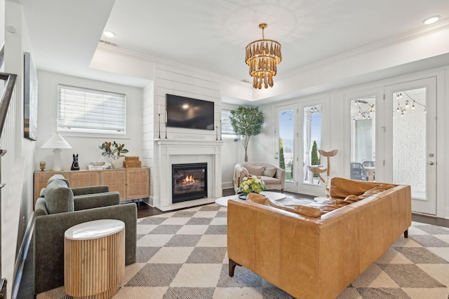 living room featuring an inviting chandelier, a fireplace with flush hearth, visible vents, and crown molding