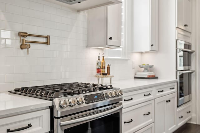 kitchen featuring light stone countertops, appliances with stainless steel finishes, white cabinets, and decorative backsplash