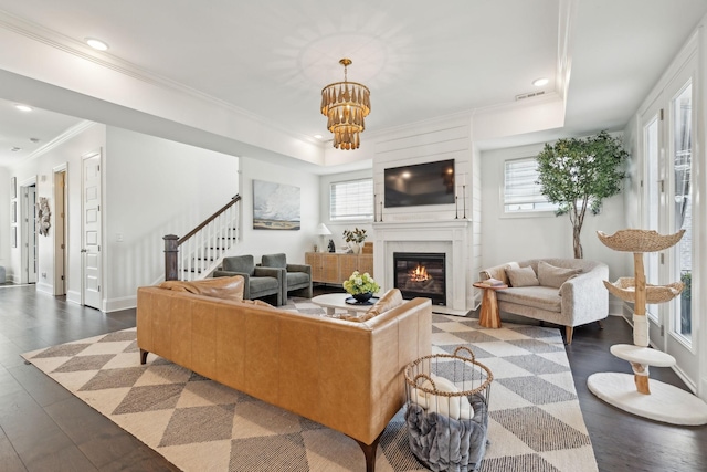 living room with dark wood-type flooring, a healthy amount of sunlight, crown molding, and visible vents