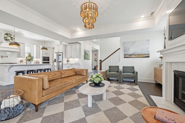 living room with recessed lighting, a fireplace, a tray ceiling, and ornamental molding