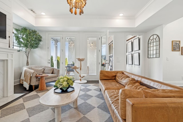 living room with a raised ceiling, visible vents, crown molding, and baseboards