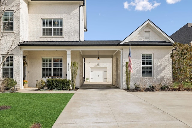 view of front of house with a front yard, concrete driveway, and brick siding