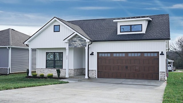 modern inspired farmhouse with stone siding, roof with shingles, an attached garage, and driveway