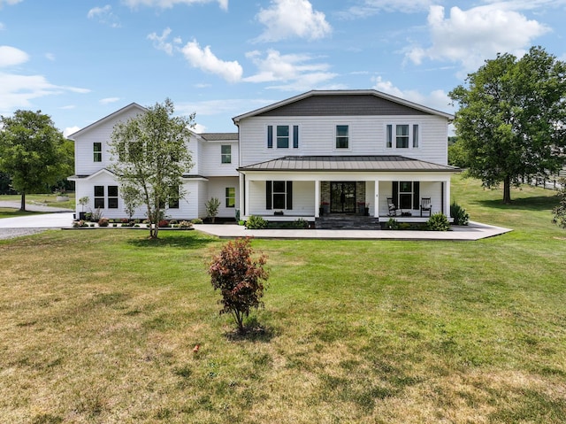 view of front of property featuring covered porch, metal roof, a front lawn, and a standing seam roof