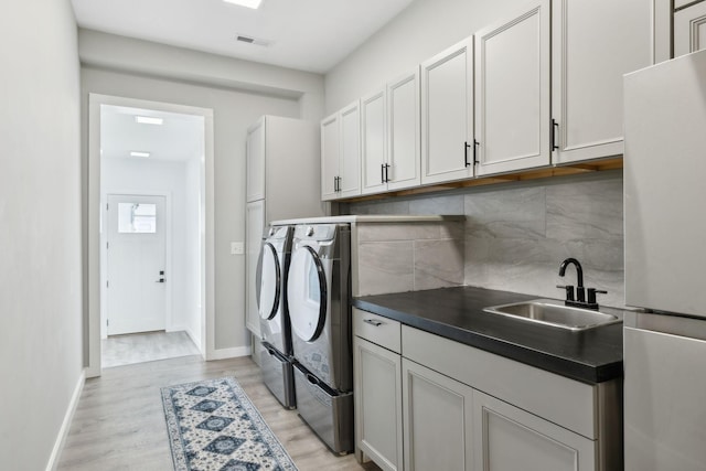 7609 Nolensville Rd, Nolensville, TN 37135 - washroom with baseboards, visible vents, light wood-type flooring, separate washer and dryer, and a sink