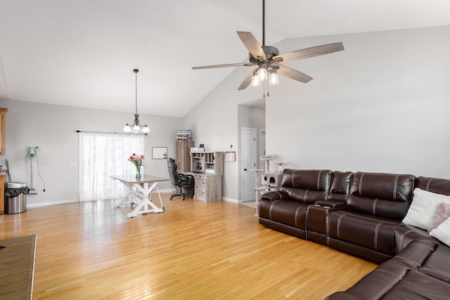 living area with ceiling fan with notable chandelier, high vaulted ceiling, light wood-type flooring, and baseboards