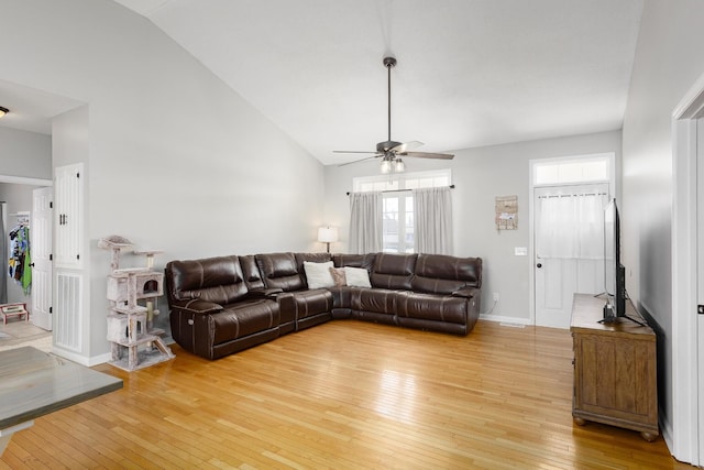 living area featuring high vaulted ceiling, light wood finished floors, a ceiling fan, and baseboards