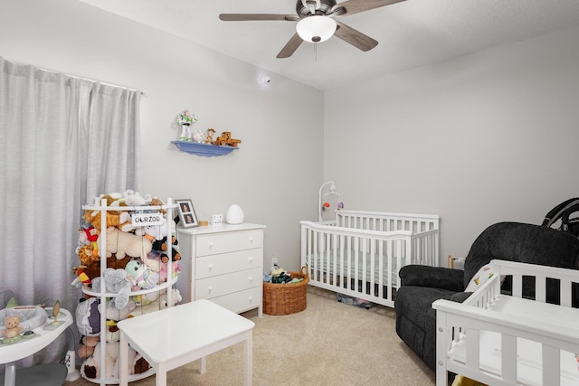 bedroom with a nursery area, ceiling fan, and light colored carpet