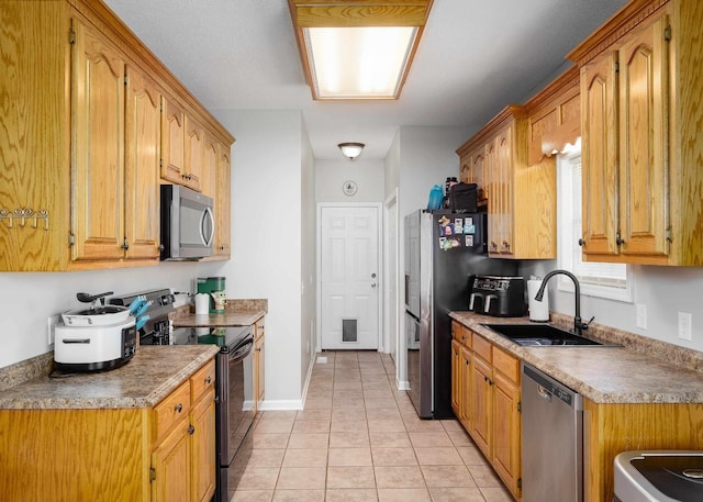 kitchen with light tile patterned flooring, stainless steel appliances, a sink, baseboards, and brown cabinets