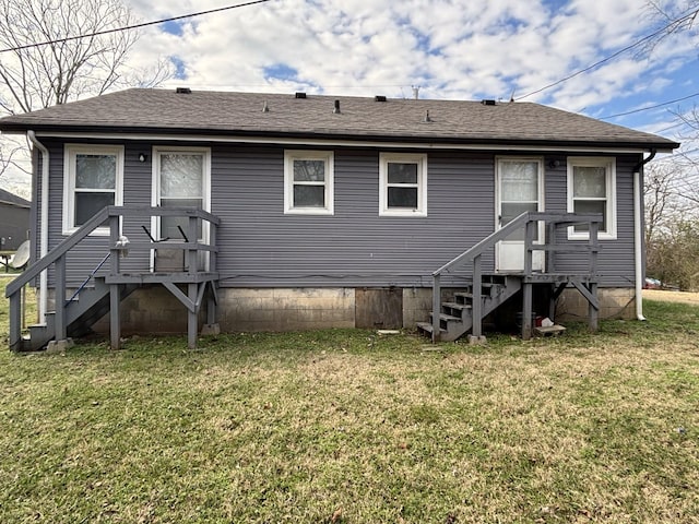 back of house featuring entry steps, a shingled roof, and a lawn