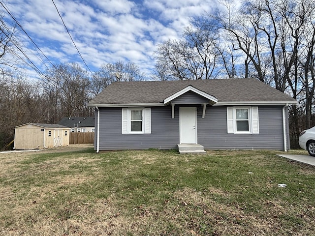 view of front of property with roof with shingles, a storage unit, a front yard, entry steps, and an outdoor structure