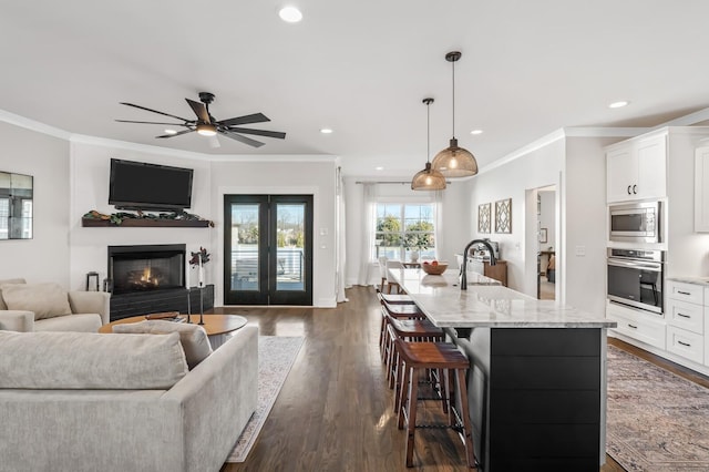 kitchen featuring light stone countertops, white cabinetry, stainless steel appliances, and decorative light fixtures