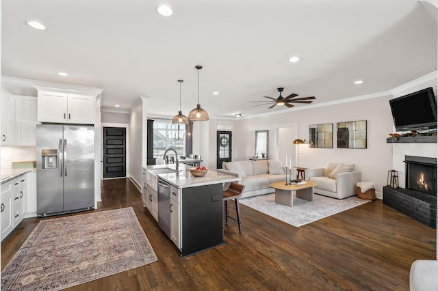 kitchen with white cabinets, appliances with stainless steel finishes, open floor plan, a breakfast bar area, and pendant lighting