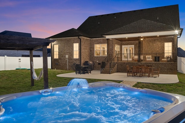 back of house at dusk with a patio area, brick siding, fence, and an outdoor bar