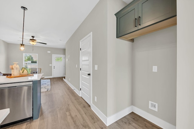 kitchen featuring light wood-style flooring, baseboards, light countertops, stainless steel dishwasher, and hanging light fixtures