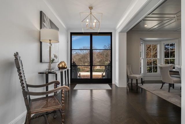 foyer entrance with baseboards, ornamental molding, dark wood-style flooring, and an inviting chandelier