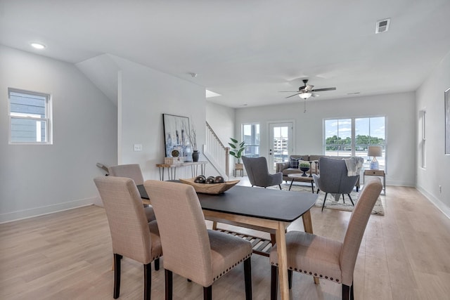 dining area featuring baseboards, visible vents, stairway, and light wood finished floors