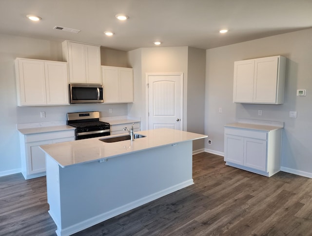 kitchen with stainless steel appliances, visible vents, white cabinets, a sink, and an island with sink